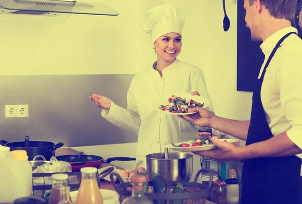 Woman cook giving salad to waitress
