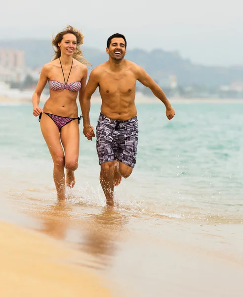 Happy couple running in swimwear