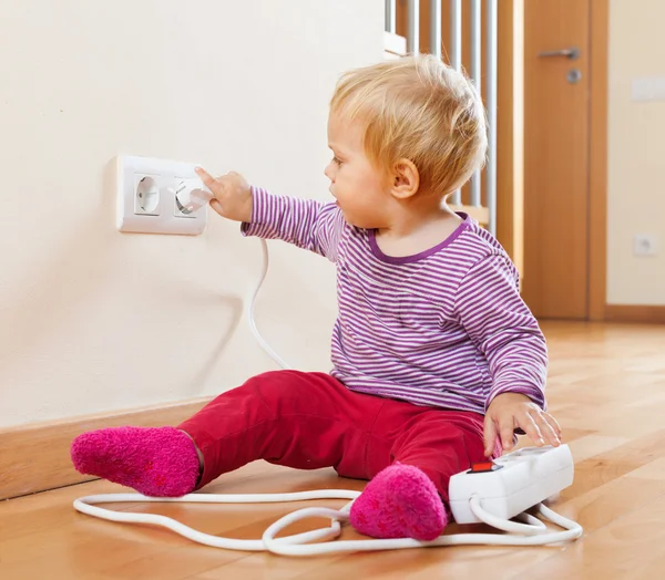 Toddler playing with extension cord and outlet