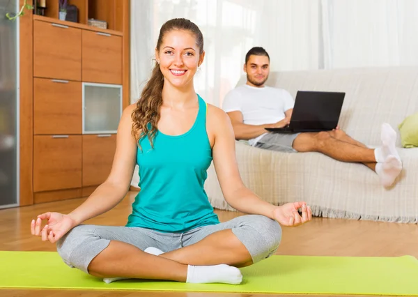 Female in yoga position and lazy guy on sofa