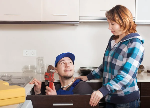 Housewife watching as worker repairing  water lines