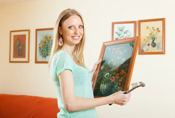Happy woman hanging the art picture