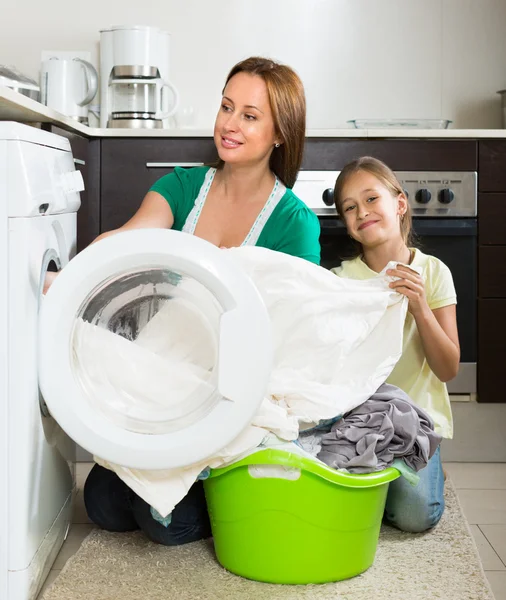 Woman with daughter  washing clothes