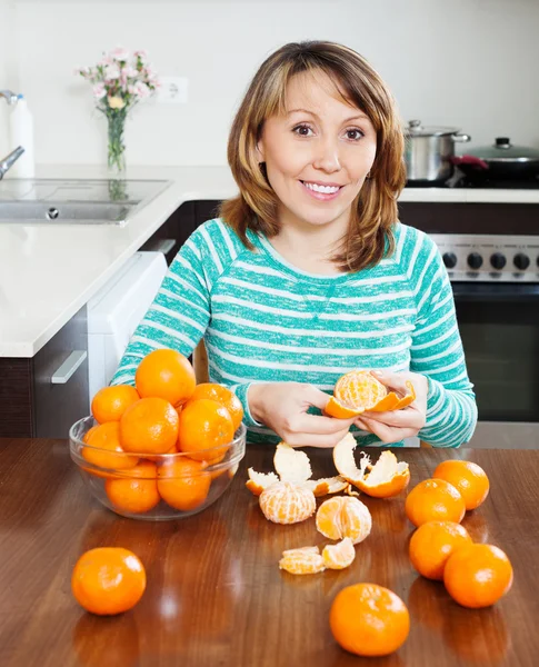 Smiling woman eating tangerines