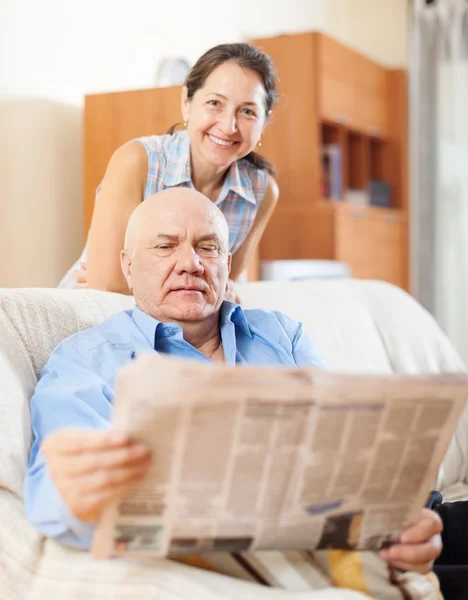 Mature couple reading newspaper together