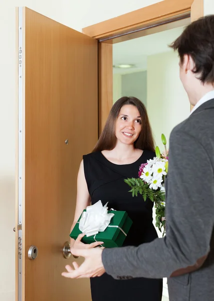 Girl giving flowers and gift to man