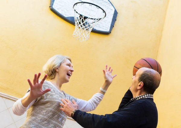 Mature couple playing basketball