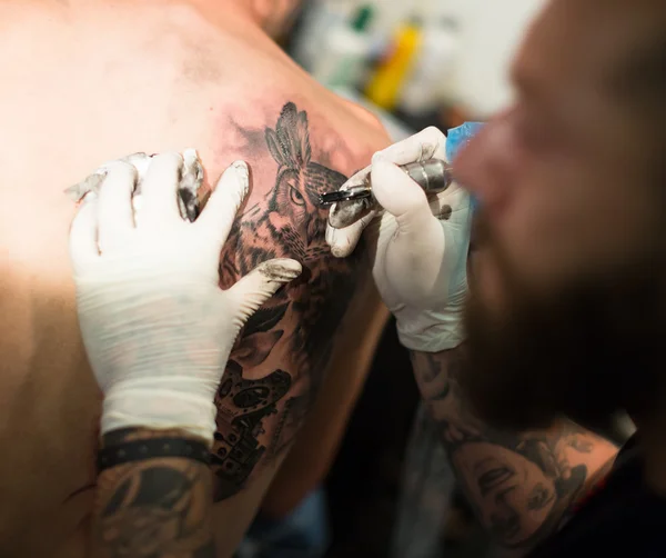 Artist doing  tattoo on client
