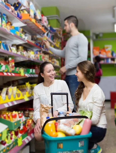 Customers standing near shelves with canned goods at shop