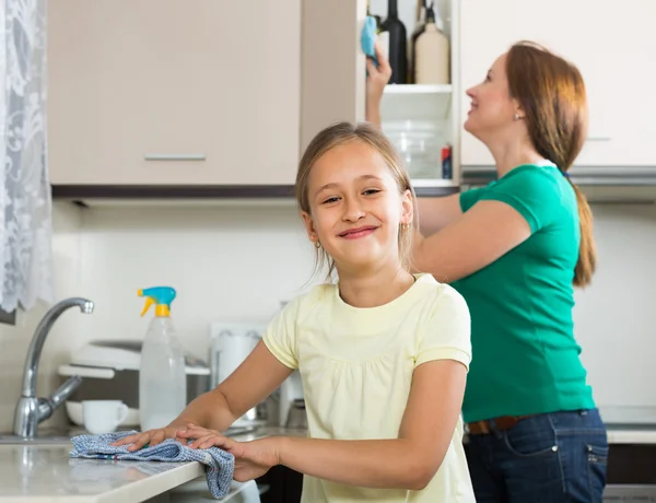 Little girl helping mother at kitchen