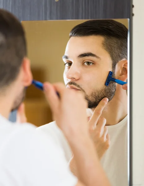 Man shaving face with razor