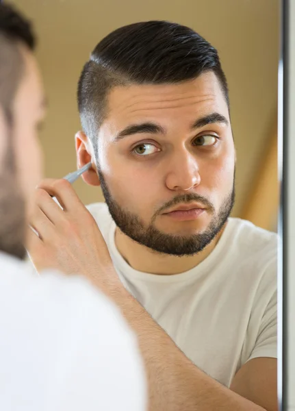 Guy removing hair in his ear