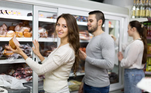 Customers near fridge with meat products