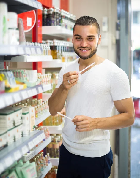 Smiling young man buying perfume