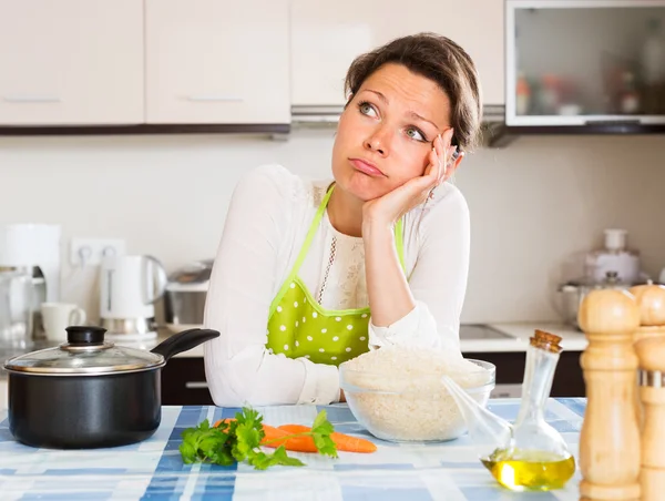 Pensive woman cooks rice with vegetables