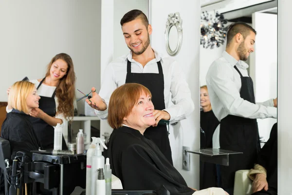 Elderly woman cuts hair at the hair salon