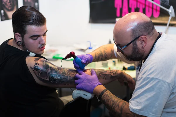 Tattoo master doing  tattoo on man  arm