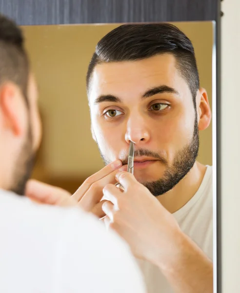 Man removing nose hair