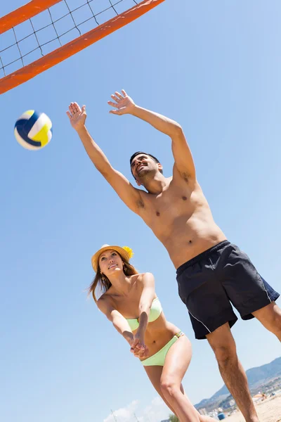 Girl and guy playing volleyball at beach