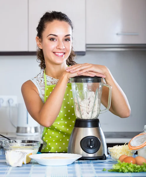 Smiling girl using kitchen blender for cooking
