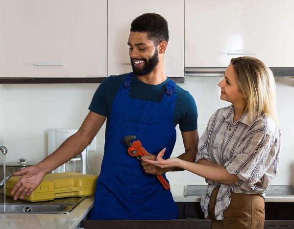 Plumber and housewife in kitchen