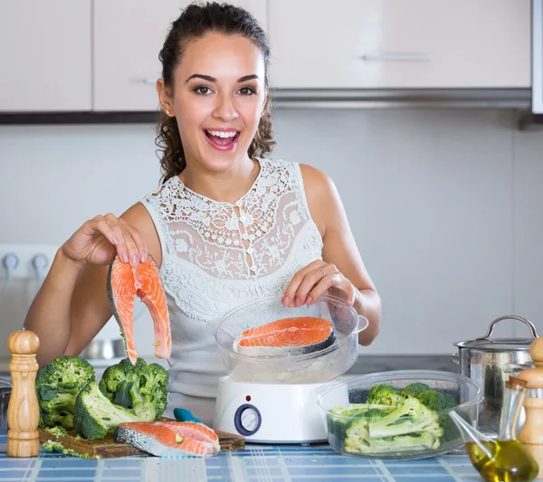 Woman steaming salmon and vegetables