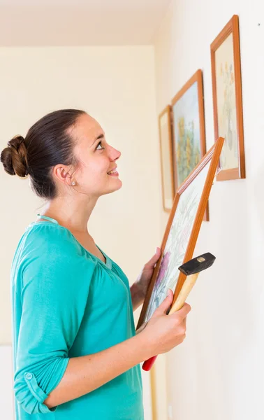 Girl hanging pictures in frames on wall