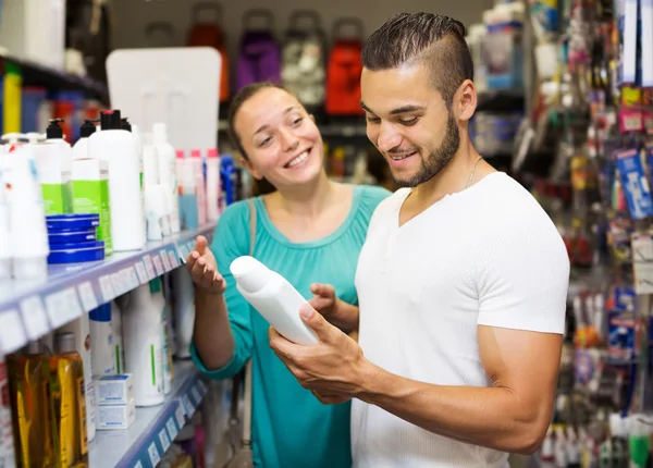 Man and woman chooses shampoo in store