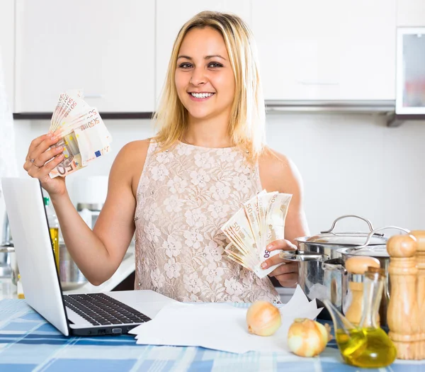 Woman with money in kitchen