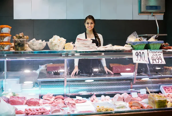 Female butcher in meat store counter