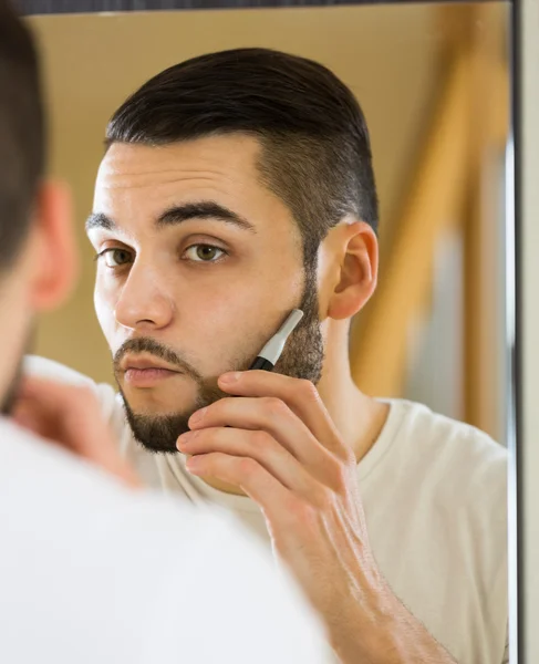 Man shaving beard with trimmer