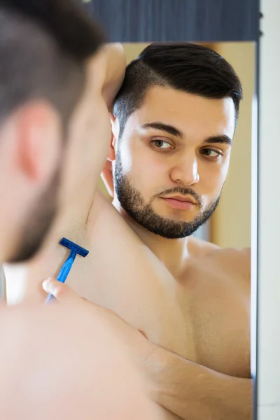 Handsome guy shaving his armpit
