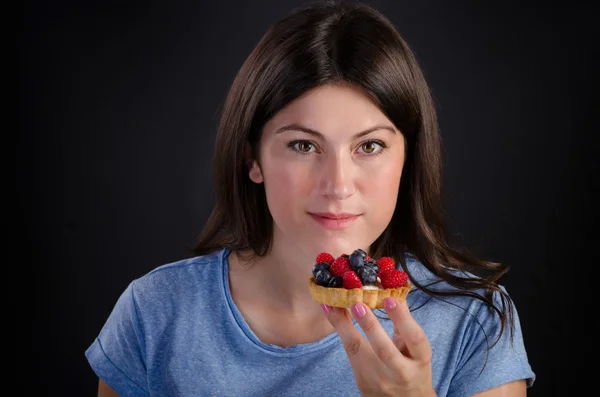 Young smiling woman eating sweet tart