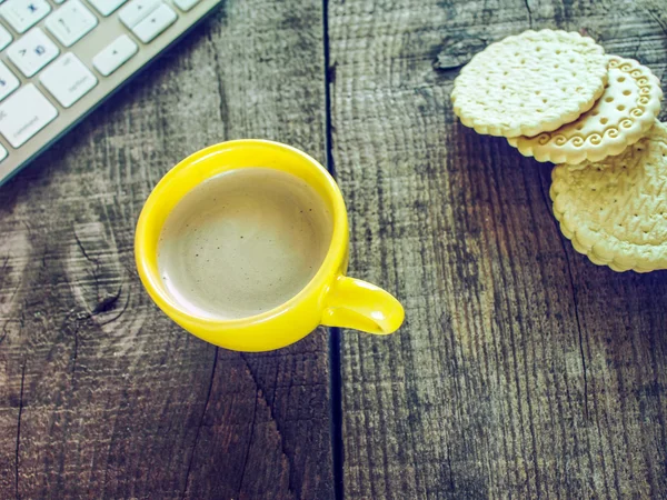 Computer keyboard, cup of coffee and biscuits