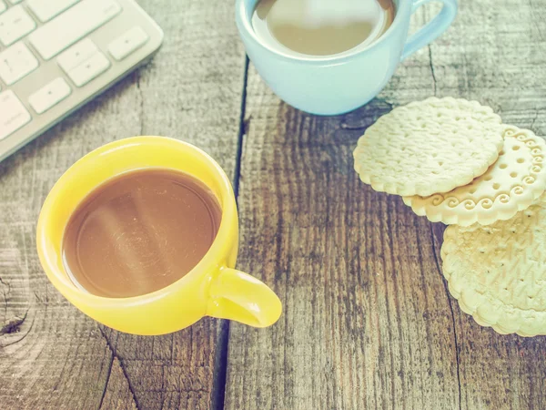 Computer keyboard, cup of coffee and biscuits