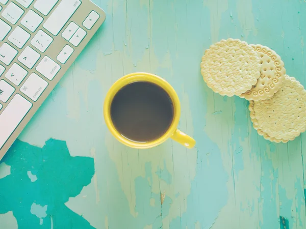 Computer keyboard, cup of coffee and biscuits