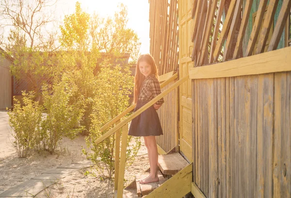Pretty little girl on stairs of wooden house