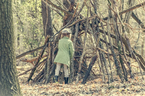 Little  girl builds  hut in  woods