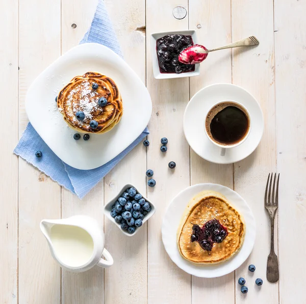 Pancakes with blueberry and coffee on table