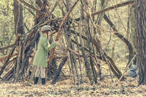 Ittle cute girl builds a hut in the woods