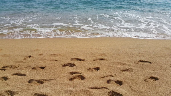 Waves and footprints on the sand beach