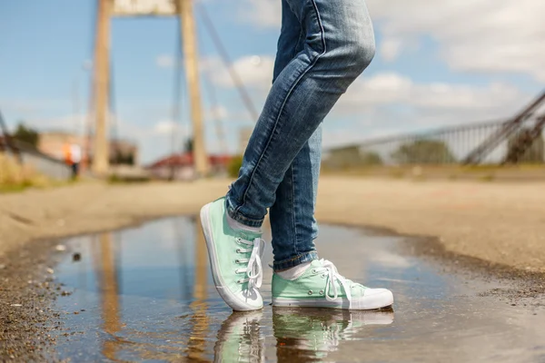 Woman in sport shoes standing in a puddle