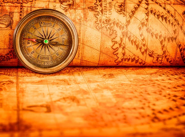 Vintage compass lies on an ancient world map.