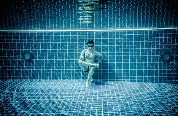 Persons lies under water in a swimming pool