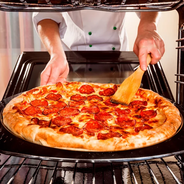 Chef prepares pepperoni pizza