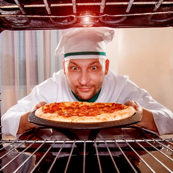 Chef prepares pizza in the oven