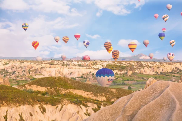 Multi-colored balloons fly over rocks