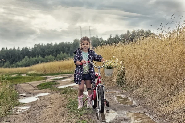 Girl with bicycle on rural road