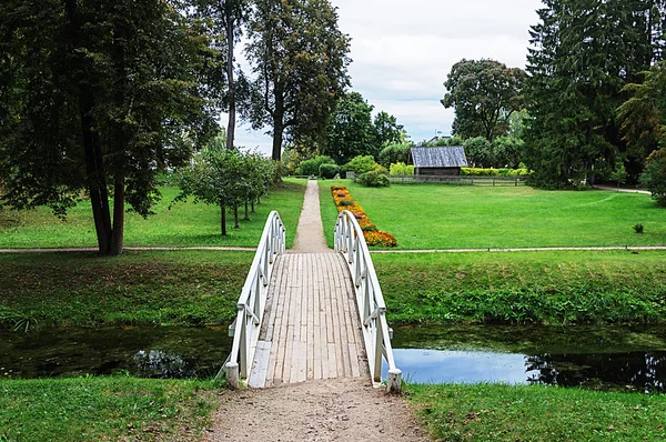 Footpath in old park with white wooden bridge