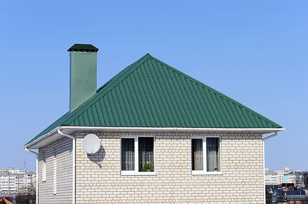 White brick house with green roof